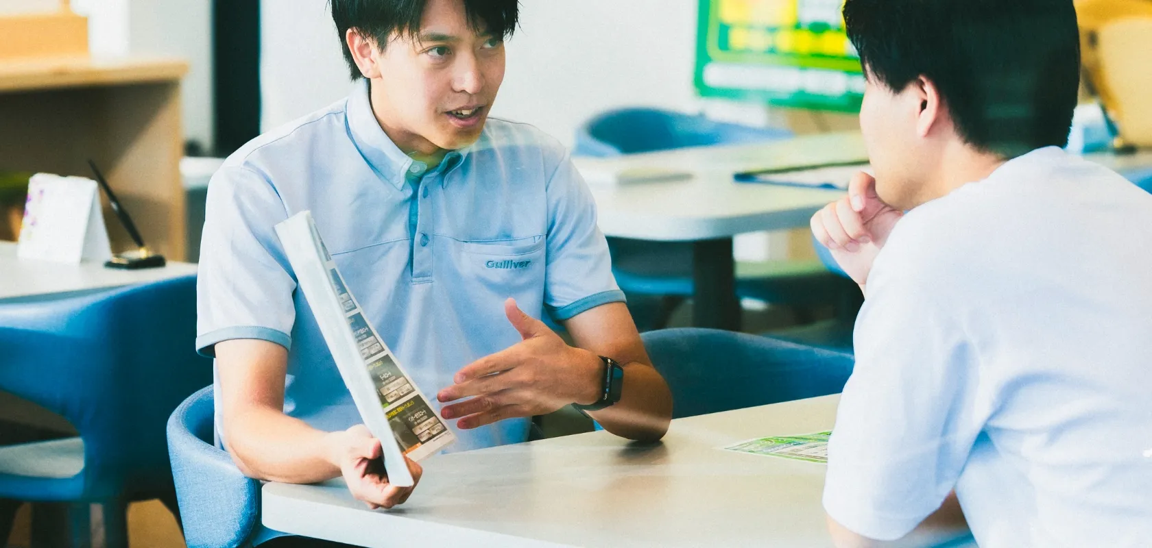 写真：男性社員が店舗に来店したお客様と商談している様子