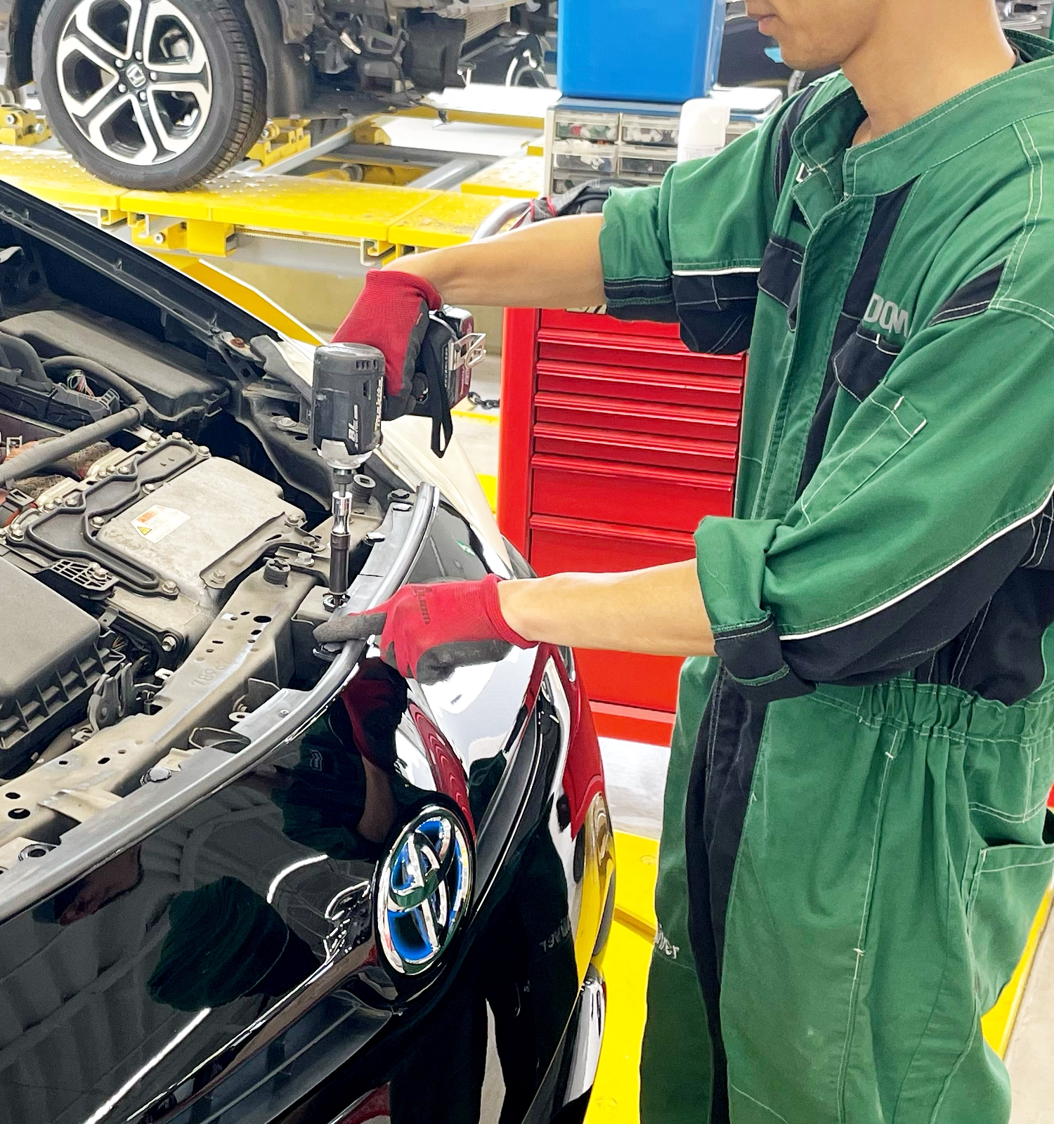 写真：工場で男性の整備士が工具を使い、車の内部を整備している様子