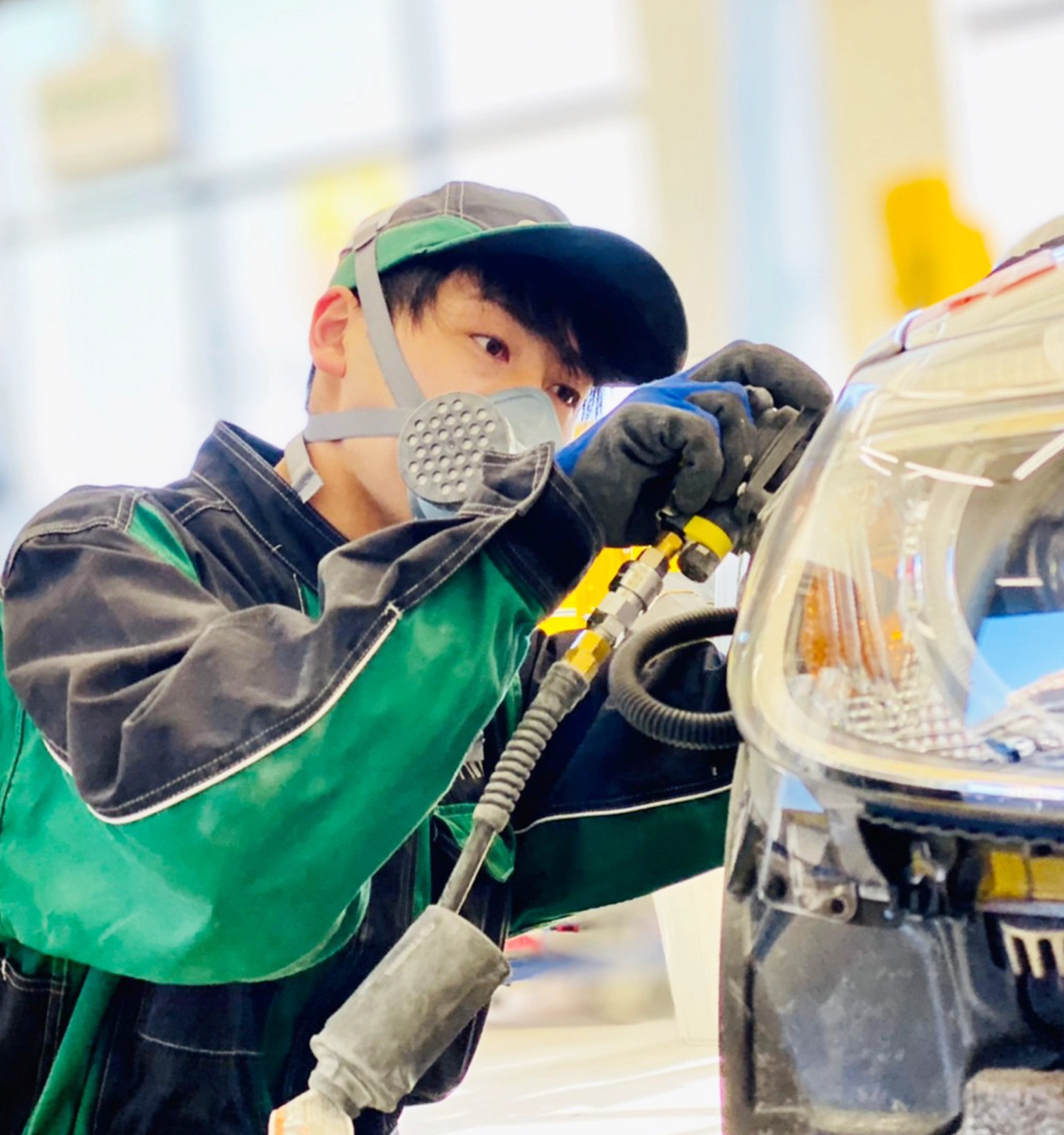写真：工場で男性の整備士が機材を使い、塗装作業をしている様子